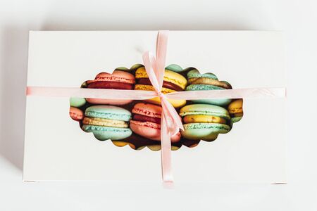Sweet almond colorful pink blue yellow green macaron or macaroon dessert cake in gift box isolated on white background. French sweet cookie. Minimal food bakery concept. Flat lay top view copy spaceの写真素材