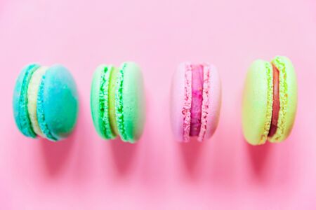 Sweet almond colorful pink blue yellow green macaron or macaroon dessert cake isolated on trendy pink pastel background. French sweet cookie. Minimal food bakery concept. Flat lay top view copy spaceの写真素材