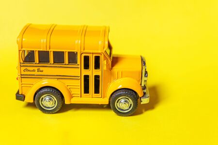 Simply design yellow classic toy car school bus isolated on yellow colorful background. Safety daily transport for kids. Back to school concept. Education symbol. Copy spaceの写真素材