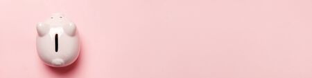Simply minimal design pink piggy bank isolated on pink pastel background. Saving investment budget wealth business retirement financial money banking concept. Flat lay top view copy space bannerの写真素材