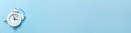 Simply minimal design ringing twin bell classic alarm clock Isolated on blue pastel background. Rest hours time of life good morning night wake up awake concept. Flat lay top view copy space bannerの写真素材