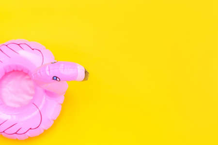 Summer beach composition. Simply minimal design with pink Inflatable flamingo isolated on yellow background. Pool float party, trendy celebrity fashion concept. Flat lay top view copy spaceの写真素材