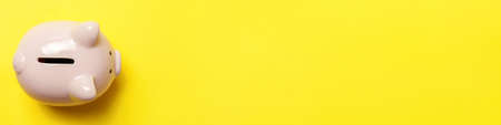 Simply minimal design pink piggy bank isolated on yellow background. Saving investment budget wealth business retirement financial money banking concept. Flat lay top view copy space bannerの写真素材
