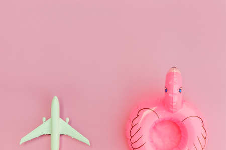 Summer beach composition. Minimal simple flat lay with plane and Inflatable flamingo isolated on pastel pink background. Vacation travel adventure trip concept. Top view copy spaceの写真素材