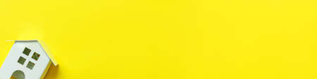 Simply minimal design with miniature white toy house isolated on yellow colourful background. Mortgage property insurance dream home concept. Flat lay top view copy space bannerの写真素材