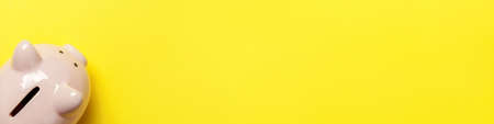 Simply minimal design pink piggy bank isolated on yellow background. Saving investment budget wealth business retirement financial money banking concept. Flat lay top view copy space bannerの写真素材