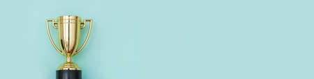 Simply flat lay design winner or champion gold trophy cup isolated on blue pastel colorful...
