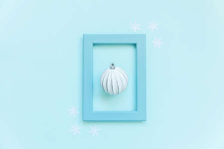 Simply minimal composition winter objects ornament ball in blue frame isolated on blue pastel trendy...