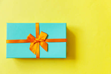 Christmas New Year birthday valentine celebration present romantic concept. Simply minimal design blue gift box isolated on yellow colorful background. Flat lay top view copy spaceの写真素材
