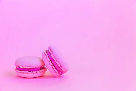Sweet almond colorful unicorn pink macaron or macaroon dessert cake isolated on trendy pink pastel background. French sweet cookie. Minimal food bakery concept. Copy spaceの写真素材