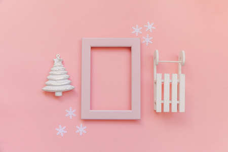 Simply minimal composition winter objects pink frame ornament fir tree sled isolated on pink pastel background. Christmas New Year december time for celebration concept. Flat lay top view mock upの写真素材