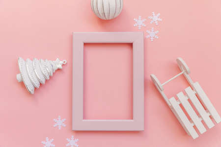Simply minimal composition winter objects pink frame ornament fir tree sled isolated on pink pastel background. Christmas New Year december time for celebration concept. Flat lay top view mock upの写真素材