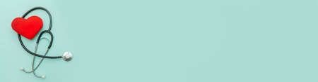 Simply minimal design with medicine equipment stethoscope or phonendoscope and red heart isolated on pastel blue background. Instrument device for doctor. Health care life insurance concept bannerの写真素材