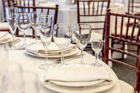 Fancy table set for dinner with napkin glasses in restaurant, luxury interior background. Wedding elegant banquet decoration and items for food arranged by catering service on white tablecloth tableの写真素材