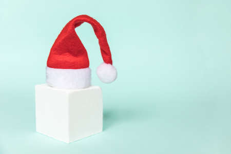 Simply minimal composition winter object Santa hat and cube shapes geometric form podium isolated blue pastel background. Christmas New Year december time for celebration concept. Mockup copy spaceの写真素材