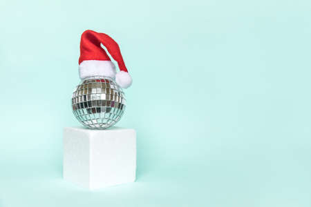 Simply minimal composition disco ball in Santa hat and cube shapes geometric form podium isolated blue pastel background. Christmas New Year december time for celebration concept. Mockup copy spaceの写真素材