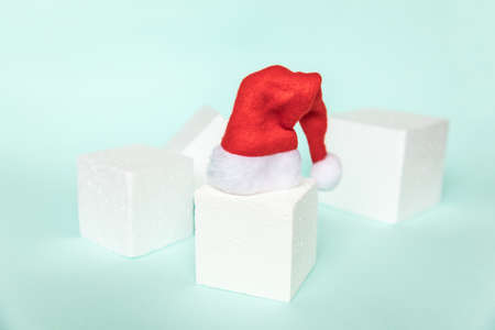 Simply minimal composition winter object Santa hat and cube shapes geometric form podium isolated blue pastel background. Christmas New Year december time for celebration concept. Mockup copy spaceの写真素材