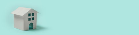 Simply minimal design with miniature white toy house isolated on blue pastel background. Mortgage property insurance dream home concept. Copy space bannerの写真素材
