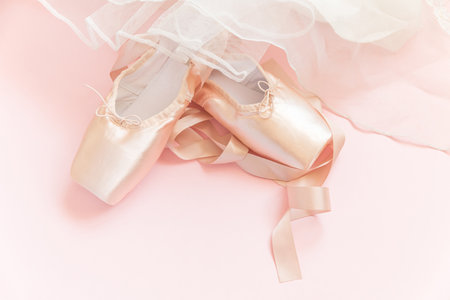 New pastel beige ballet shoes with satin ribbon and tutut skirt isolated on pink background. Ballerina classical pointe shoes for dance training. Ballet school concept. Top view flat lay copy spaceの写真素材