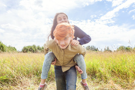 Summer holidays vacation happy people concept. Loving couple having fun in nature outdoors. Happy young man piggybacking his girlfriend. Happy loving couple embracing outdoor at summertimeの写真素材