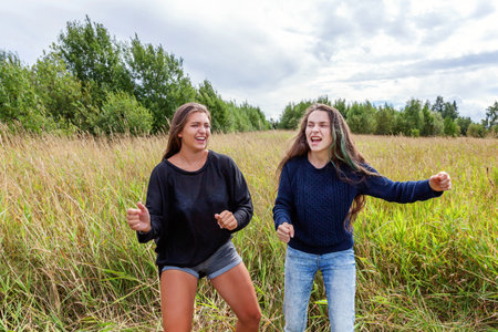Summer holidays vacation happy people concept. Group of two girl friends sisters dancing hugging and having fun together in nature outdoors. Lovely moments best friendの写真素材