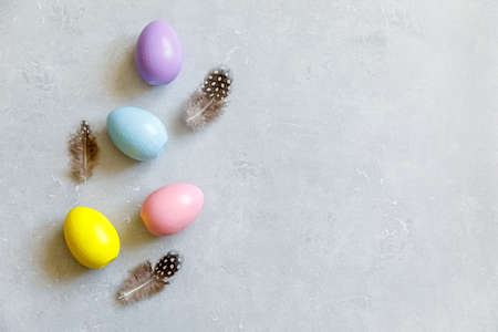 Happy Easter concept. Preparation for holiday. Colorful decorated easter eggs feather on concrete stone grey background. Simple minimalism flat lay top view copy spaceの写真素材