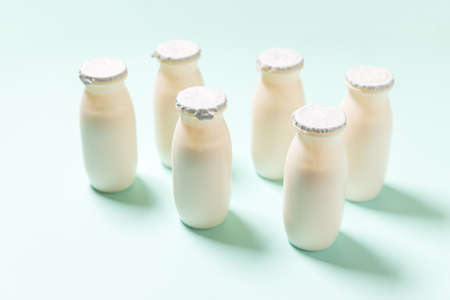 Small bottles with probiotics and prebiotics dairy drink on blue background. Production with biologically active additives. Fermentation and diet healthy food. Bio yogurt with useful microorganismsの写真素材