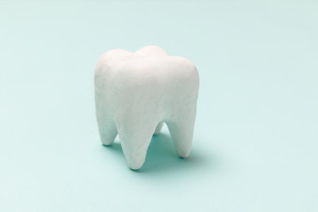 Health dental care concept. White healthy tooth model isolated on pastel blue background. Teeth whitening, dental oral hygiene, teeth restoration, dentist day. Copy spaceの写真素材