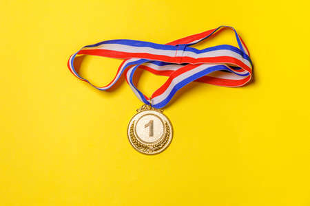Simply flat lay design winner or champion gold trophy medal isolated on yellow colorful background. Victory first place of competition. Winning or success concept. Top view copy spaceの写真素材
