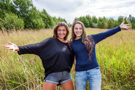 Summer holidays vacation happy people concept. Group of two girl friends sisters dancing hugging and having fun together in nature outdoors. Lovely moments best friendの写真素材