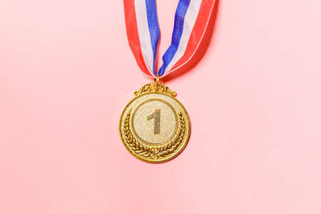 Simply flat lay design winner or champion gold trophy medal isolated on pink colorful background. Victory first place of competition. Winning or success concept. Top view copy spaceの写真素材