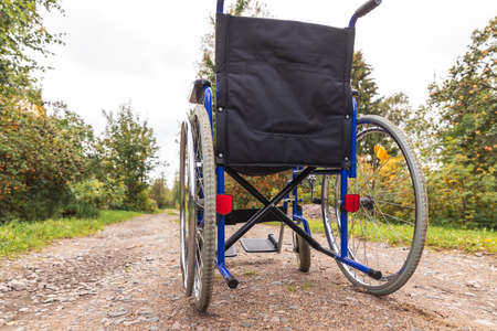 Empty wheelchair standing on road waiting for patient services. Invalid chair for disabled people parked outdoor in nature. Handicap accessible symbol. Health care medical conceptの写真素材