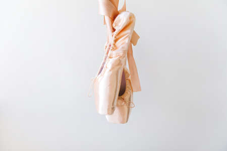 New pastel beige ballet shoes with satin ribbon isolated on white background. Ballerina classical pointe shoes for dance training. Ballet school concept, Copy spaceの写真素材