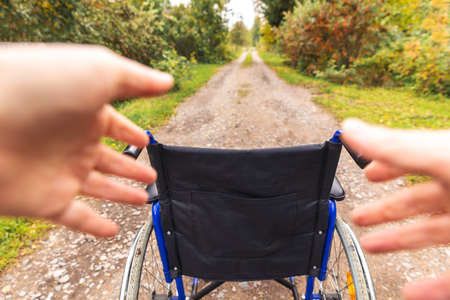 Hands holding empty wheelchair in hospital park waiting for patient services. Wheel chair for person with disability parked outdoor. Accessible for person with disability. Health care medical conceptの写真素材