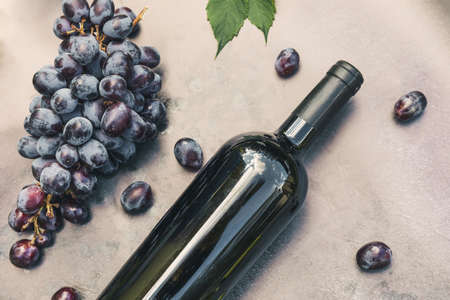 Bottle of red wine, green vine, wineglass and ripe grape on vintage dark stone table background. Top view copy space for text. Wine shop wine bar winery or wine tasting concept.の写真素材