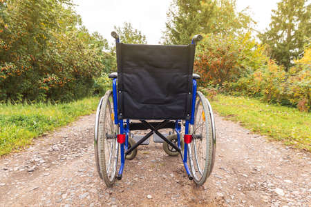 Empty wheelchair standing on road waiting for patient services. Wheel chair for people person with disability parked outdoor. Accessible for person with disability. Health care medical concept.の写真素材
