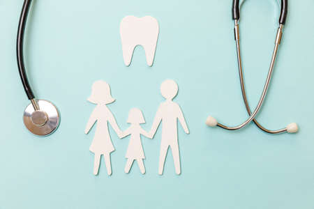 Family health dental care concept. Flat lay stethoscope white healthy tooth family cutout symbol model isolated on blue background. Check up by dentist doctor child. Dental oral hygiene, dentist dayの写真素材