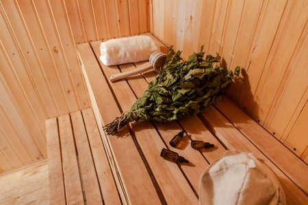 Traditional old Russian bathhouse SPA Concept. Interior details Finnish sauna steam room with traditional sauna accessories set towel birch broom scoop felt. Relax country village bath conceptの写真素材