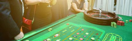 Group of people behind roulette gambling table in luxury casino. Friends playing poker at roulette table with tape measure. Vegas games nightlife lucky winning concept. Bannerの写真素材