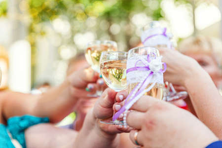 Cheers. Group of people drinking and toasting in restaurant. Hands holding glasses of champagne and wine making toast. Christmas new year wedding holiday party time. Celebration and nightlife conceptの写真素材