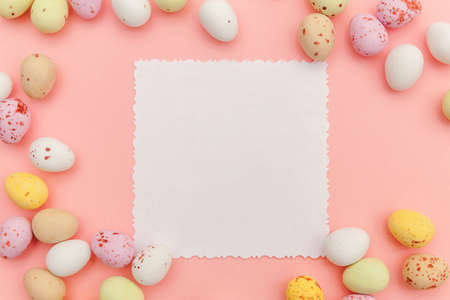 Happy Easter concept. Candy chocolate eggs and jellybean sweets with mockup empty poster isolated on...