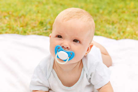 Cute little newborn girl lying on tummy on blanket in lawn on sunny summer day outdoor. Infant...