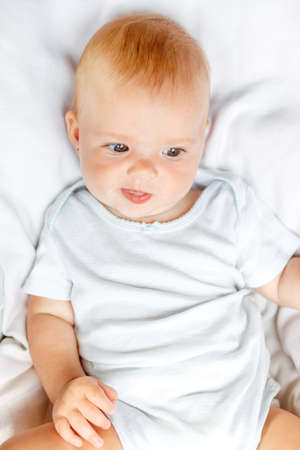 Cute little newborn girl with smiling face looking at camera on white background. Infant baby...