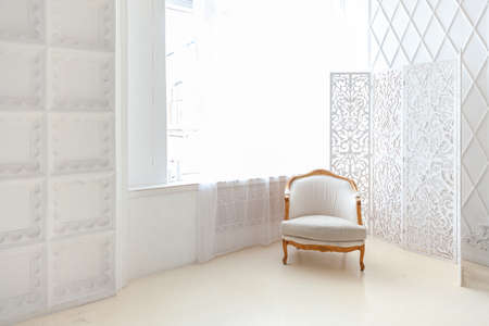 Stylish loft bedroom interior. Spacious design apartment with light walls large windows and armchair. Clean modern decoration with elegant furniture in minimalist Scandinavian styleの写真素材