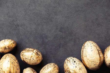 Happy Easter concept. Preparation for holiday. Golden Easter eggs on grunge scratched dark black...