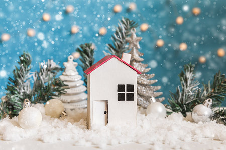Abstract Advent Christmas Background. Toy model house and winter decorations ornaments on blue background with snow. Christmas with family at home conceptの写真素材