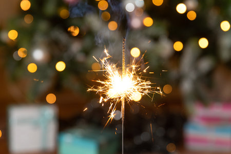 Christmas glittering sparklers candle burns in Christmas tree background. Xmas lighting decoration at home indoor. Festive Magic sparks lights for holiday party. Christmas eve with fireworksの写真素材