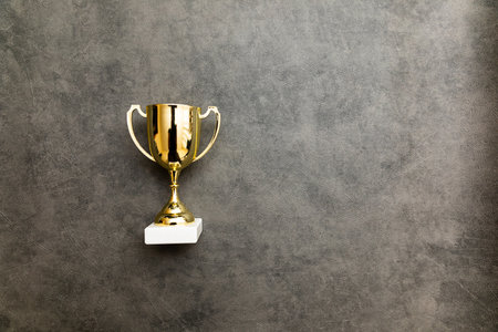 Simply flat lay design winner or champion gold trophy cup on concrete stone grey background. Victory first place of competition. Winning or success concept. Top view copy spaceの写真素材