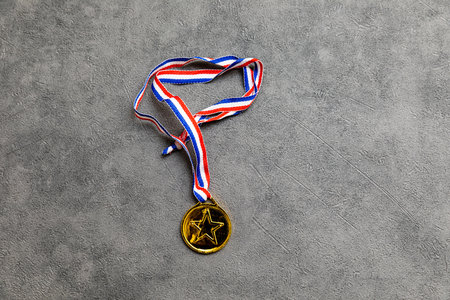 Simply flat lay design winner or champion gold trophy medal on concrete stone grey background. Victory first place of competition. Winning or success concept. Top view flat lay copy spaceの写真素材