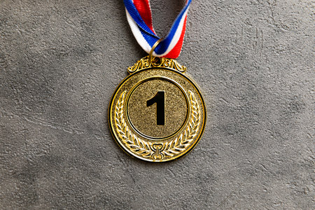 Simply flat lay design winner or champion gold trophy medal on concrete stone grey background....
